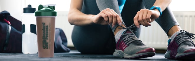 Person tying show next to SP Complete Chocolate shake.